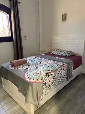 a bedroom with a bed with a flowered blanket on it at Villa Muhammad in Quseir