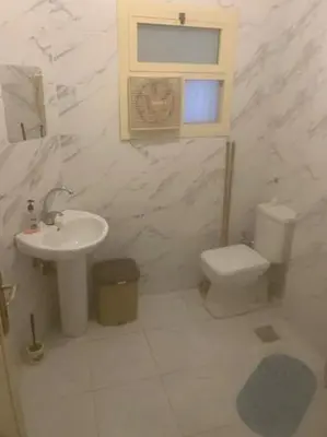 a white bathroom with a sink and a toilet at ALHASANI APARTMENT in Hurghada