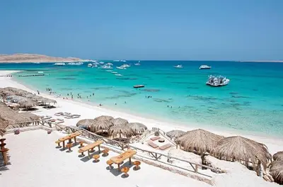 a beach with many straw umbrellas and the ocean at ALHASANI APARTMENT in Hurghada