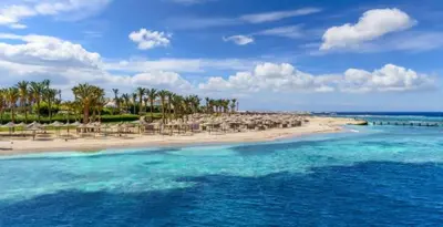 a beach with umbrellas and chairs and the ocean at ALHASANI APARTMENT in Hurghada