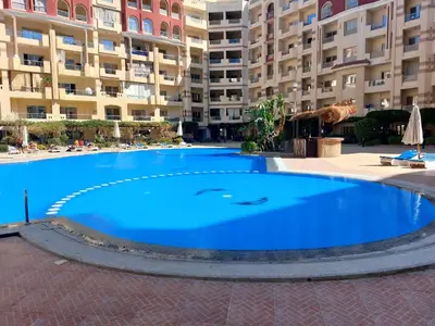 a large blue swimming pool in front of a large apartment building at Florenza Khamsin Resort Hurghada in Hurghada