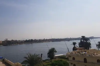 a view of a river with a building and palm trees at El Minaa Residents 5 in Luxor