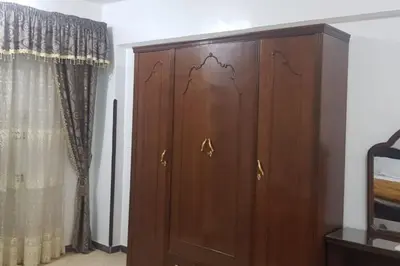 a wooden cabinet in a room with a curtain at Elminaa Residents 3 in Luxor