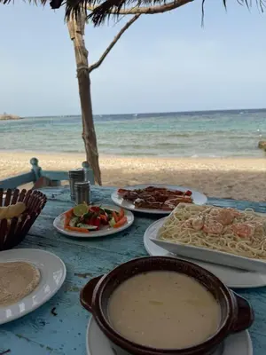 a table with plates of food on the beach at Ziena marvel camp in Quseir