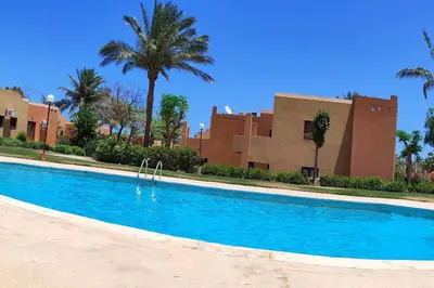 a swimming pool in front of a building with palm trees at Apartment with services Stella Beach Resort 5 star Makadi bay Egypt in Hurghada