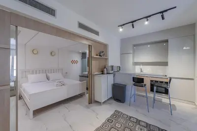 a bedroom with a white bed and a kitchen at Stylish Nest - New Marina - El Gouna in Hurghada