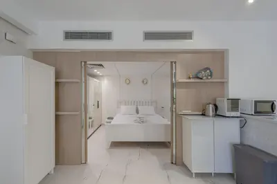 a bedroom with a white bed and a kitchen at Stylish Nest - New Marina - El Gouna in Hurghada
