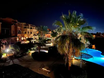 a resort with palm trees and a pool at night at Vue magnifique, confort unique in Hurghada