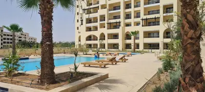 a hotel with a pool and benches in front of a building at Hurghada Aldau Heights Studio in Hurghada
