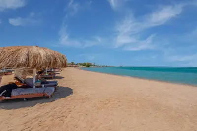 a person sitting on a beach with a laptop at Beach Front Paradise - 3 master beds - Abu Tig Marina - El Gouna in Hurghada