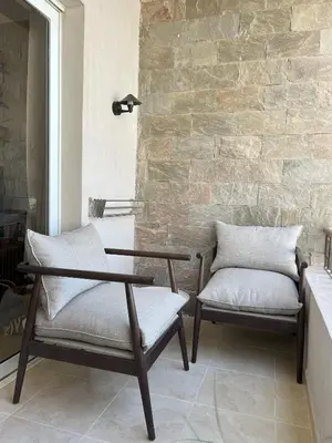 two chairs and a table in front of a stone wall at Casa De Madera - 1BR Sea & Golf View - Soma Bay in Hurghada