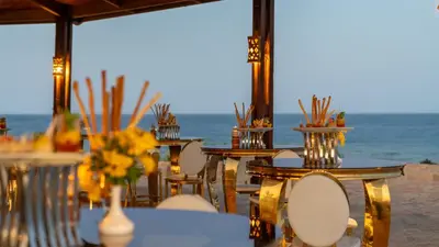 a table with chairs and flowers on the beach at Three Corners Equinox Beach Resort in Abu Dabab