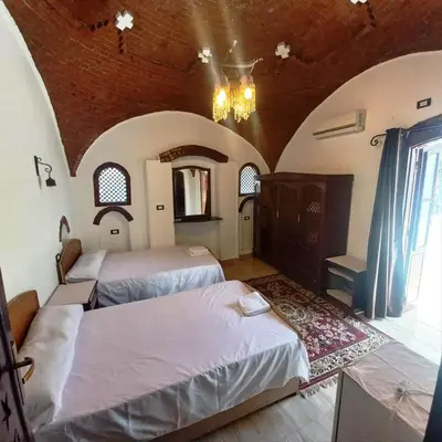 a bedroom with two beds and a chandelier at Villa Giulio - Guest House in Luxor