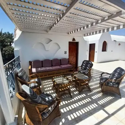 a patio with chairs and a couch on a balcony at Villa Giulio - Guest House in Luxor