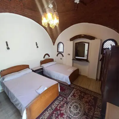 a bedroom with two beds and a chandelier at Villa Giulio - Guest House in Luxor