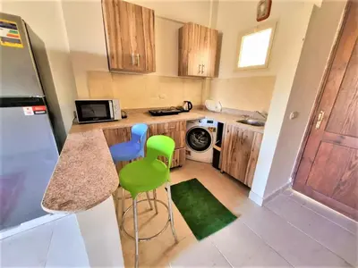 a kitchen with a counter and two green stools at 2 bedroom quiet flat at makadi heights in Hurghada