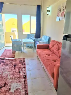 a living room with a red couch and chairs at 2 bedroom quiet flat at makadi heights in Hurghada