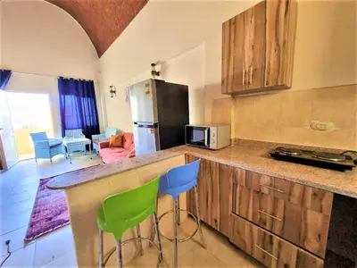 a kitchen with a counter and two green chairs at 2 bedroom quiet flat at makadi heights in Hurghada