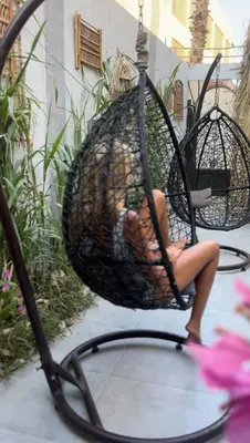 a woman sitting in a basket swing on a patio at Horizon on Mamsha 2 in Hurghada