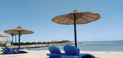 a group of blue chairs and umbrellas on a beach at Apartment in Cecelia Resort in Hurghada