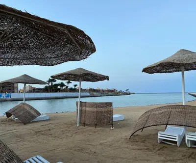 a beach with chairs and umbrellas and the ocean at Luxury Seaview Apartment with Pool Scandic Resort Hurghada in Hurghada
