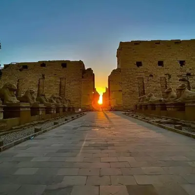 a view of the sun setting behind a building at Nile Cruise from Aswan to Luxor 3 Night And Luxor to Aswan 4 Night in Jazīrat al ‘Awwāmīyah