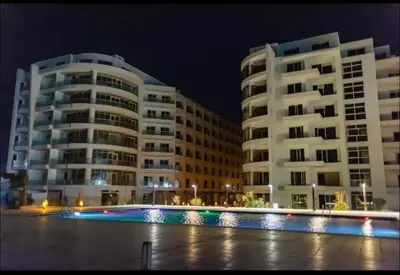 two tall buildings at night with a pool in front at Scandic Resort in Hurghada