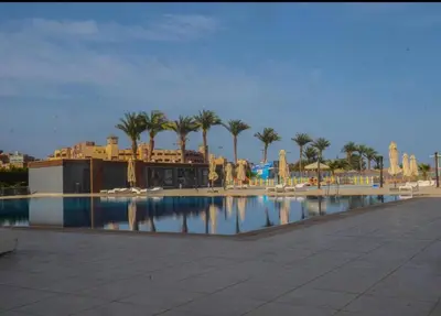 a large swimming pool with palm trees and buildings at Scandic Resort in Hurghada