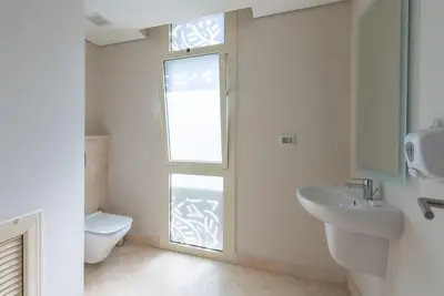 a bathroom with a toilet and a sink and a window at Modern 1BR, Mangroovy, Gouna - 1BR, Pool, & Beach in Hurghada