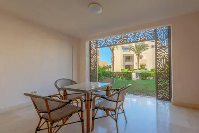 a dining room with a table and chairs in front of a door at Ground Floor 2BR Apt in Mangroovy, Pool & Beach in Hurghada
