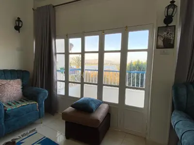 a living room with a large window and a chair at luxor Nile view duplex apartment in Luxor