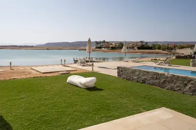a white sculpture sitting on the grass next to a pool at The Sandy Feet Sea Front in Hurghada