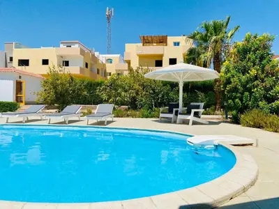 a swimming pool with an umbrella and chairs at studio for daily rent in Hurghada