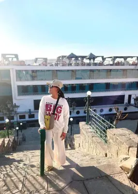 a woman standing next to a pole in front of a cruise ship at Five Star Nile Cruise from Aswan to Luxor in Aswan