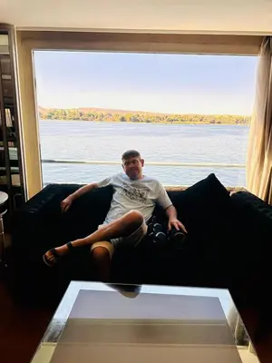 a man sitting on a couch in front of a window at Five Star Nile Cruise from Aswan to Luxor in Aswan