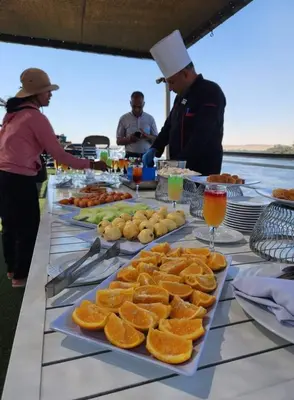 a buffet of food with oranges on a table at Five Star Nile Cruise from Aswan to Luxor in Aswan