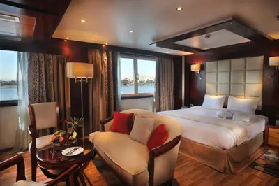 a bedroom with a bed and a chair and a table at live Nile in style Nile cruise in Luxor and Aswan in Luxor