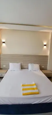 a white bed with a yellow towel on it at Hurghada Mirage Bay Hotel & Aquapark in Hurghada