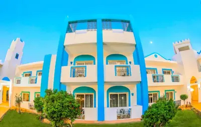 a white and blue building with trees in front of it at Hurghada Mirage Bay Hotel & Aquapark in Hurghada