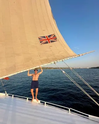 a man standing on the bow of a sail boat at 2nights Felucca from aswan to komobo temple in Aswan