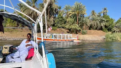 a man sitting in a boat on the water at 2nights Felucca from aswan to komobo temple in Aswan