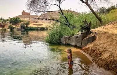 a woman standing in the water near a river at 2nights Felucca from aswan to komobo temple in Aswan