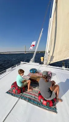 a group of people sitting on a sail boat at 2nights Felucca from aswan to komobo temple in Aswan