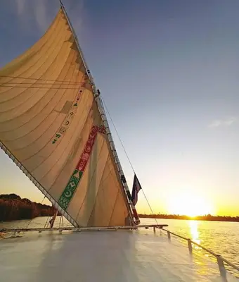 a sail boat on the water at sunset at 2nights Felucca from aswan to komobo temple in Aswan