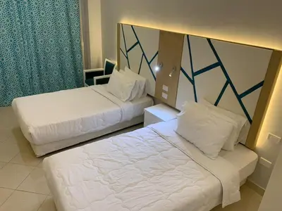 two beds in a hotel room with white sheets at Private Room Hurghada for rent beach and pools included Not Valid for Locals in Hurghada