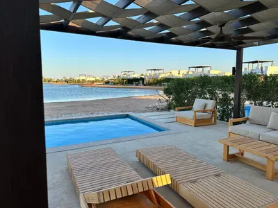 a patio with a pool and two chairs and a table at El Gouna Cyan Villa with pool n lagoon by BFG Beit Fel Gouna in Hurghada
