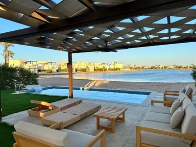 a patio with tables and chairs and a swimming pool at El Gouna Cyan Villa with pool n lagoon by BFG Beit Fel Gouna in Hurghada