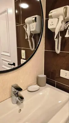 a bathroom with a sink with a mirror and lights at Florenza Khamsin Apartments in Hurghada