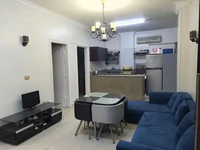 a living room with a blue couch and a kitchen at Hurghada city center in Hurghada