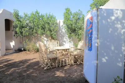a table and chairs in a yard with trees at Happy house in Luxor